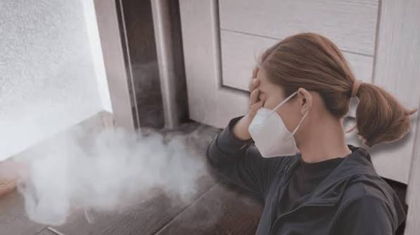 Homeowner covering their face from smoke indoors